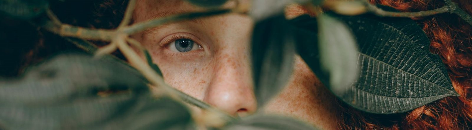 page hero, person looking through leaves